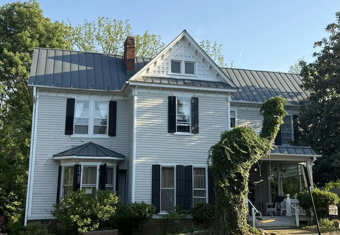 155 East Main St., The Gathering Inn White Victorian house with black shutters and topiary shaped like a dinosaur