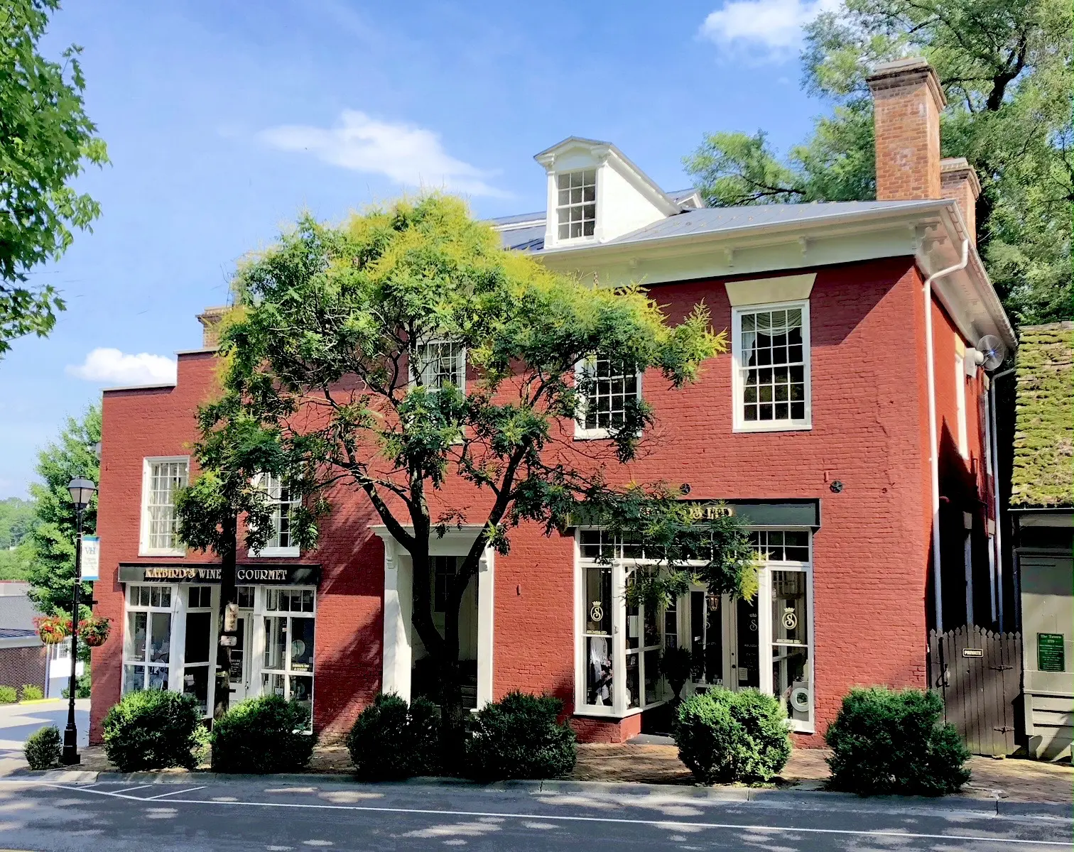 228 East Main St. Geisler House Red brick two-story historic Geisler House with white trim, a large tree,