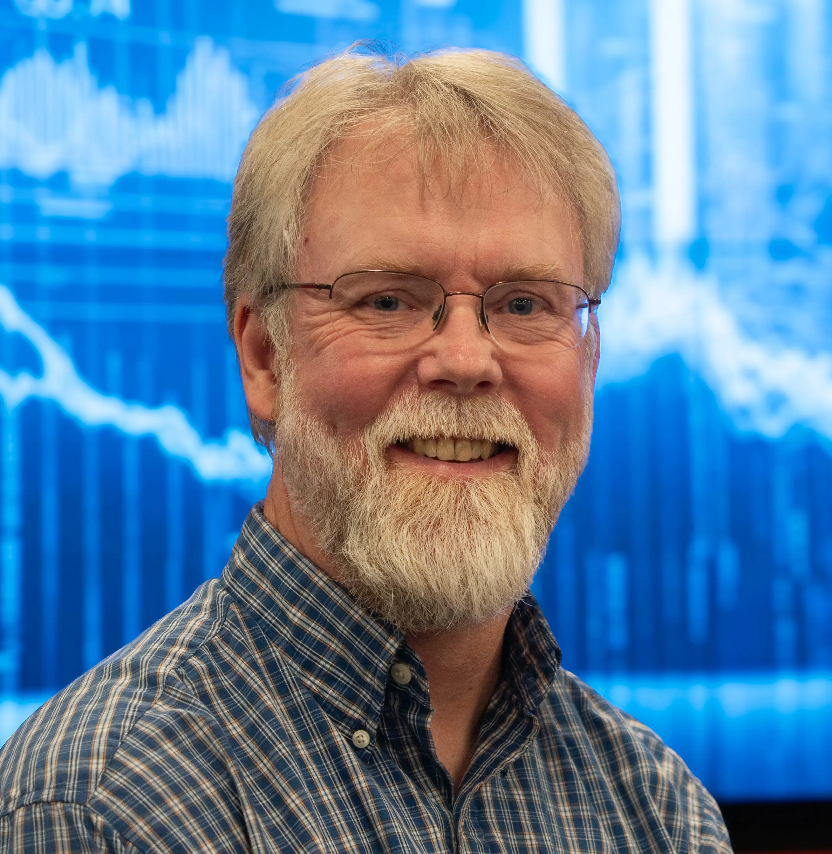 EJ_headshot Middle-aged man with glasses and beard smiling in front of blue data